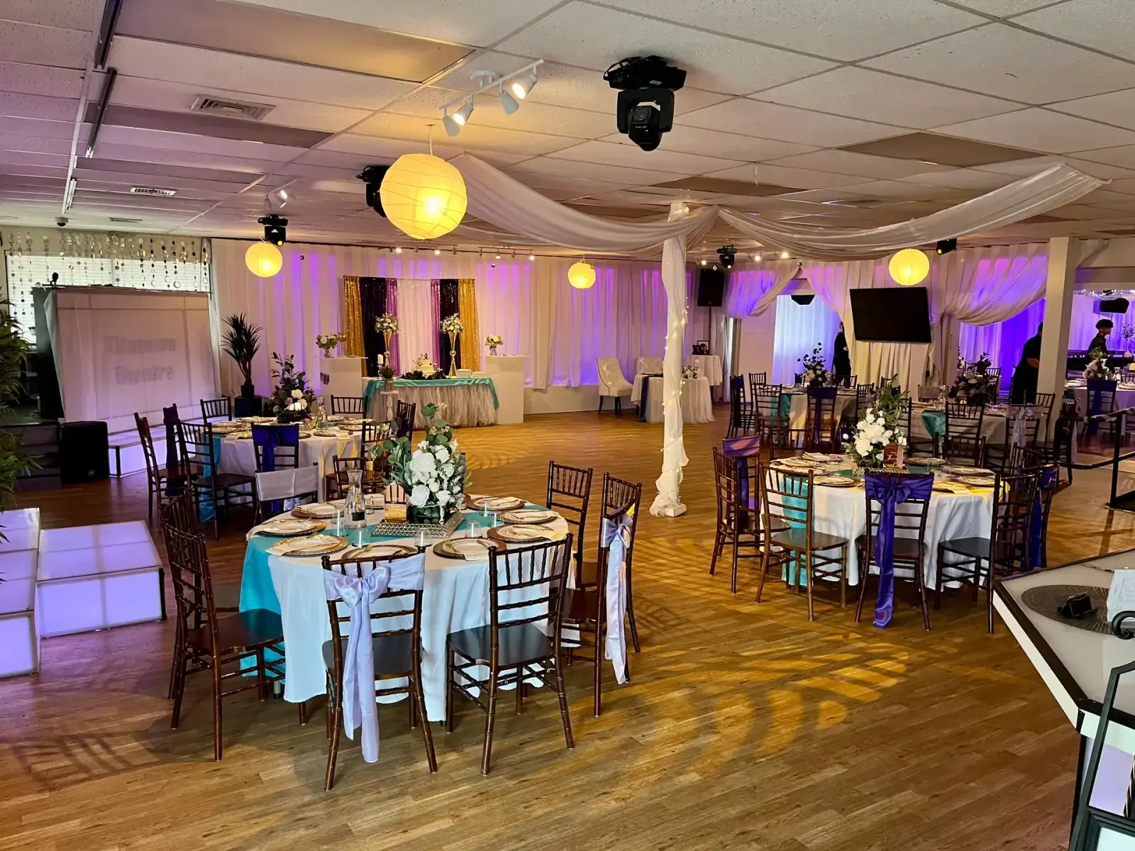 The Titanium Theatre ballroom set for an event with draped ceilings, chiavari chairs, an LED dance floor, and purple uplighting