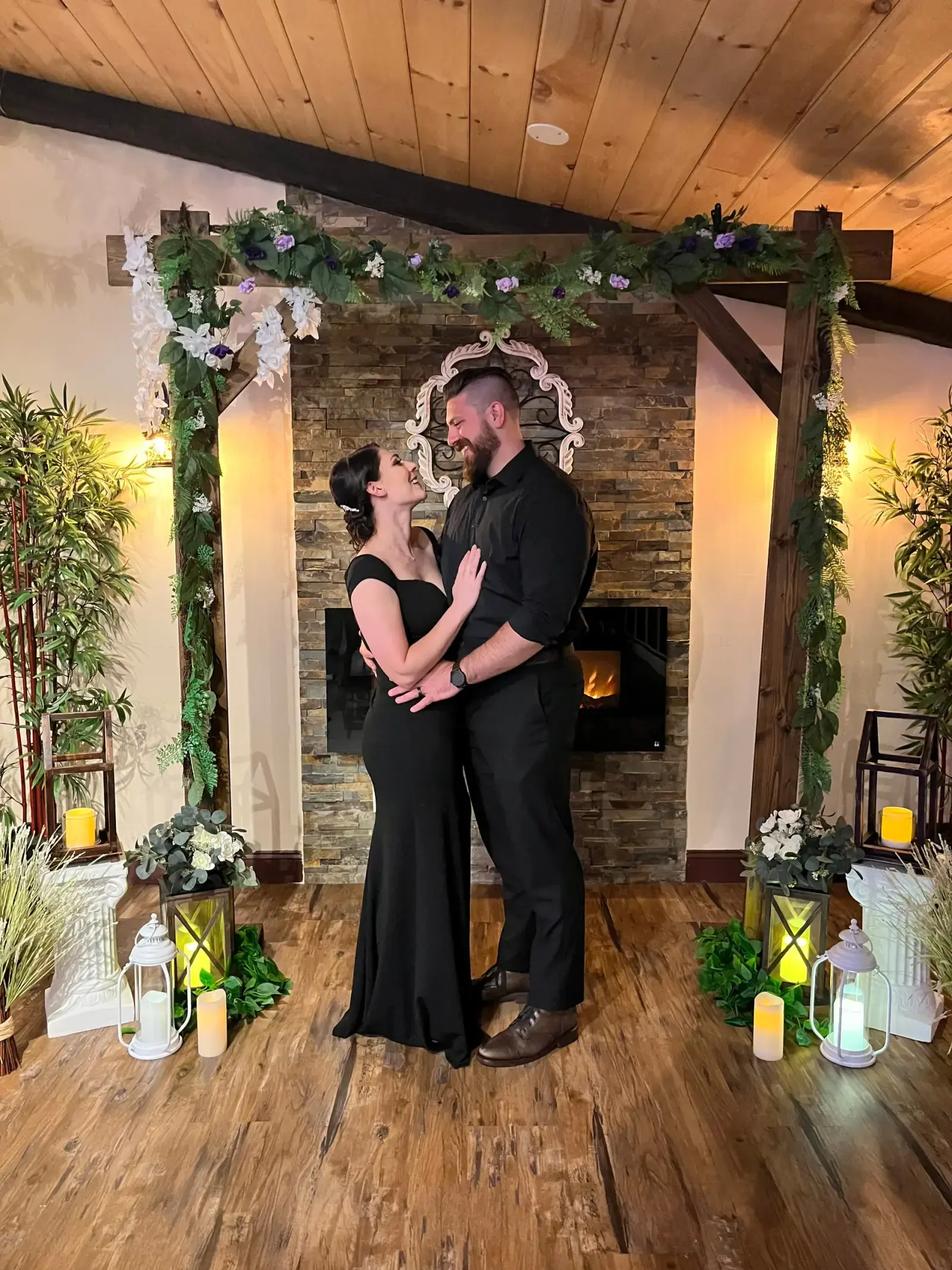 A couple embracing under a greenery-and-floral arch in the Rustic room