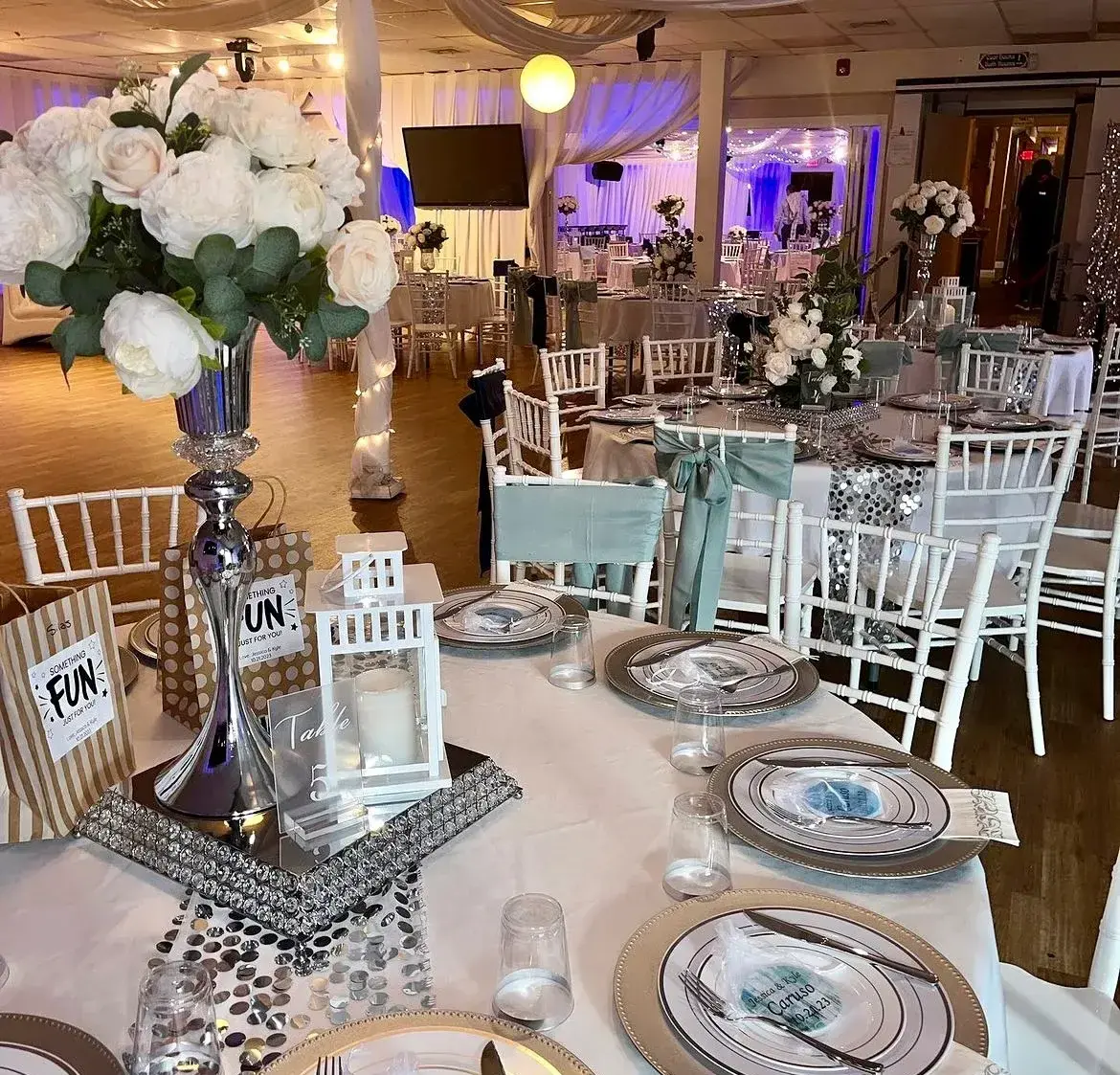 A winter-themed celebration with a balloon arch, throne chairs, and blue uplighting