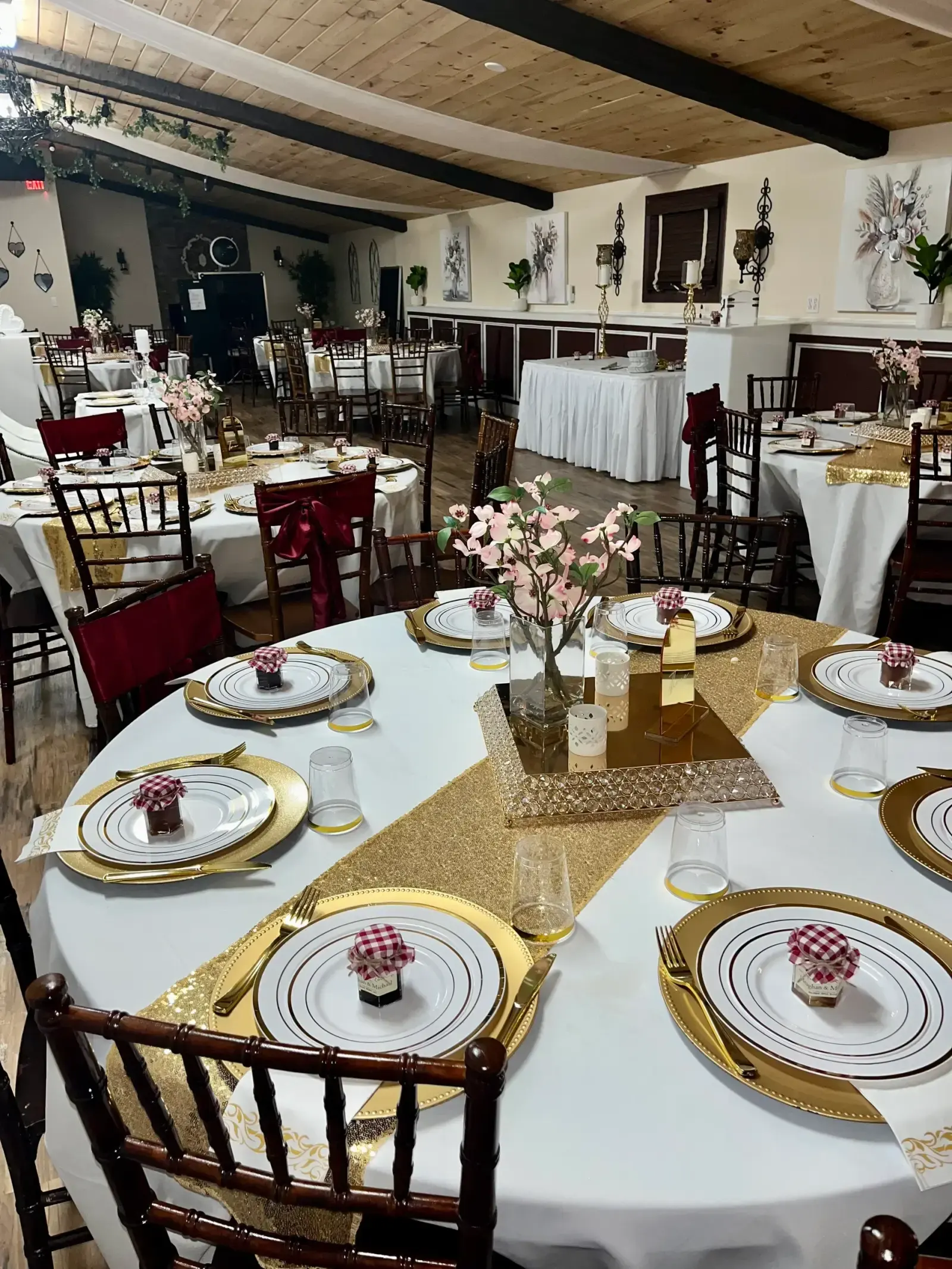 Round tables set with gold-rimmed china and sequin runners under the Rustic room's wood-beam ceiling