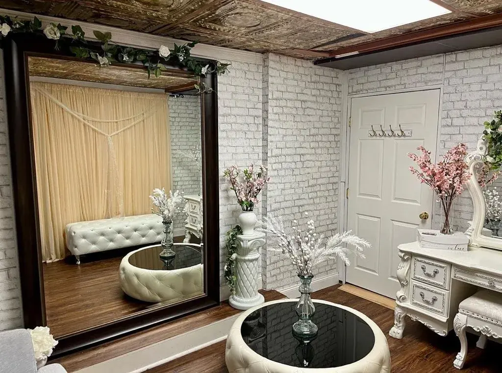 The VIP Room — a full-length mirror, tufted seating, and an ornate vanity against white brick walls
