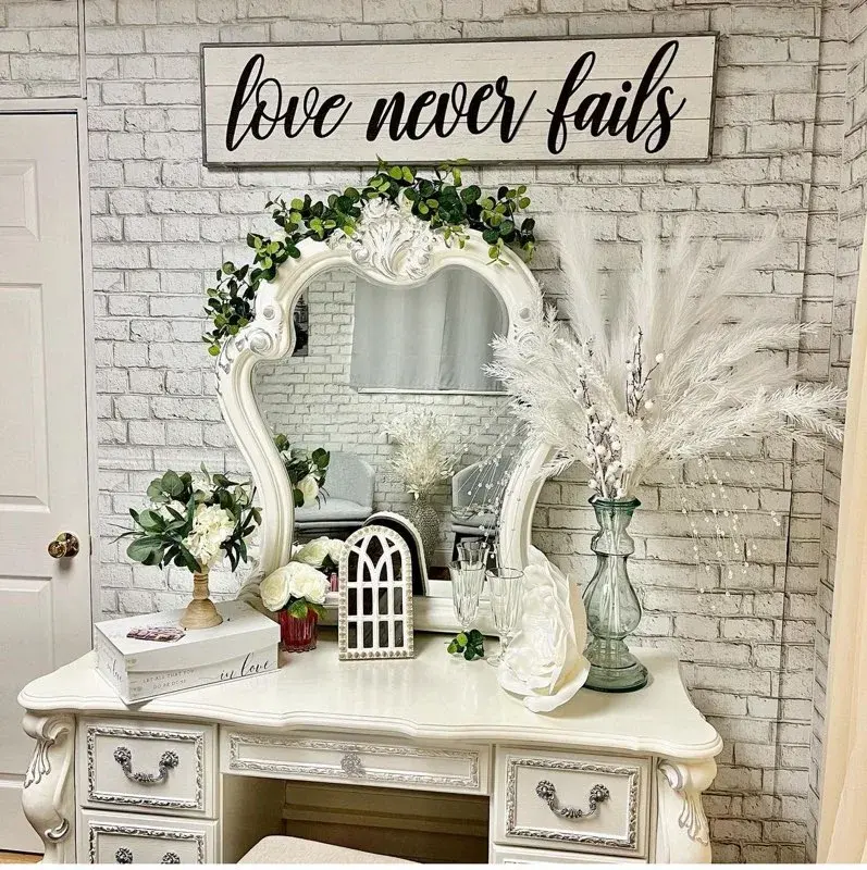 The VIP Room vanity — an ornate white dressing table and mirror beneath a "love never fails" sign