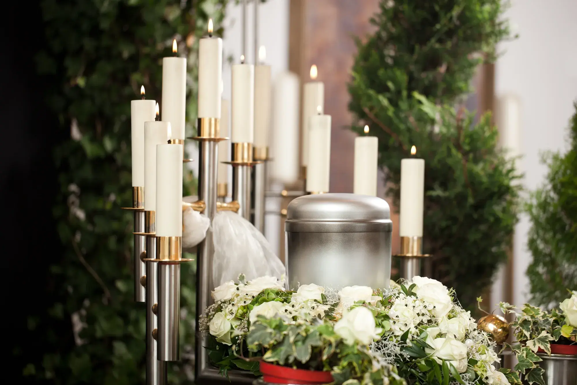Memorial candles, white roses, and an urn arranged for a celebration of life